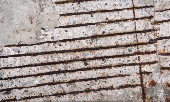 Severe concrete deterioration and spalling on a vertical structure reveals corroded steel rebar bars needing structural rehabilitation and repair work