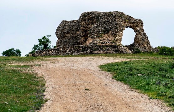 Weathered Stone Ruin with Archway in Grassy Landscape