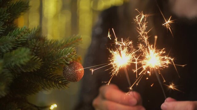 Festive mood, Happy New Year party. Woman celebrating New Year holding sparklers in her hands. 