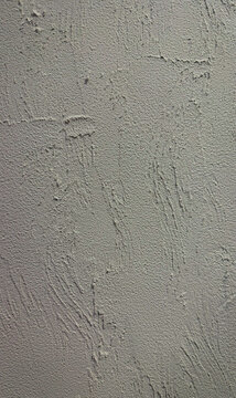 Raised ridges and shallow scratches interrupt a matte gray plaster surface. Concept of tactile wall finishes for interior and graphic design.