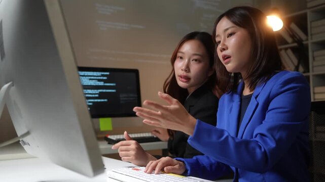 Two female asian coders collaborating on a project