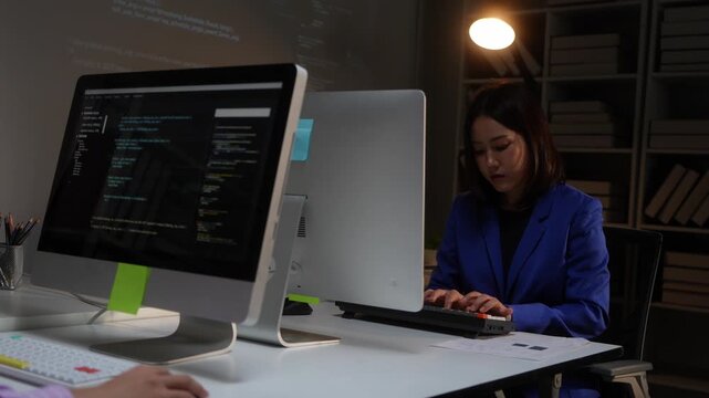 Asian women programmers working together in a dark office