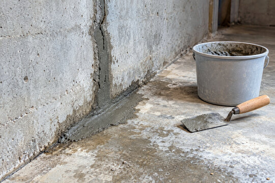 Fresh hydraulic cement patch over leaking crack at basement wall and floor joint - foundation repair and leak sealing