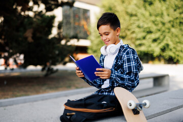 Smiling schoolboy reading blue book outdoors © djile