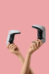 Gaming and multiplayer entertainment, two hands holding modern video game controllers for competitive play and digital leisure on a pink background © Pixel-Shot