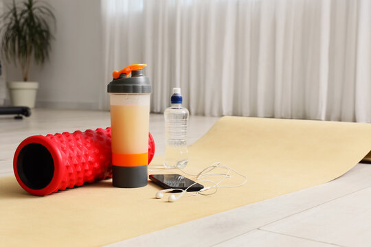 Healthy lifestyle and fitness routine, foam roller with protein shaker and water bottle on yoga mat for home workout and wellness training session