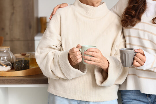 Intergenerational bonding and family support, senior mother and adult daughter drinking tea together at home with comfort and emotional connection