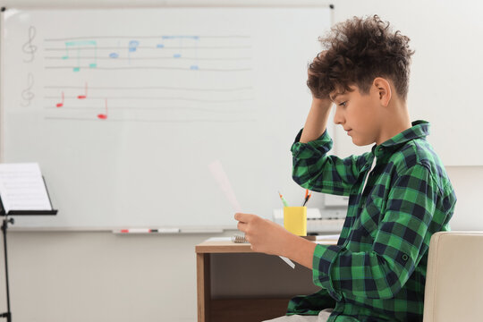 Music education and learning difficulty, boy struggling with music theory and reading sheet music in a classroom with a whiteboard and musical notes