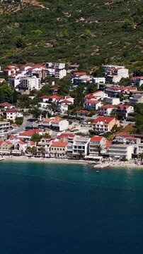 Croatia, aerial view of coastal village with red tile roofs and beach by the Adriatic Sea