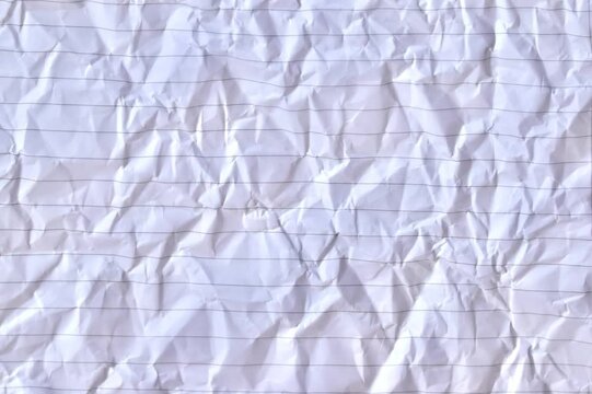 Close-up full-frame texture background of crumpled white lined notebook paper with creased folds and horizontal rules.