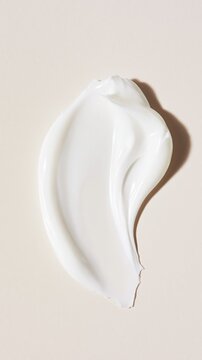 Creamy skincare texture elegantly swirled in soft, filtered light. Minimal neutral composition highlights the nourishing softness and luxurious appeal.