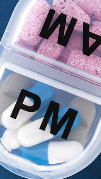 Close up view of plastic pill box organizer compartments marked with AM and PM letters for day and night medication schedule