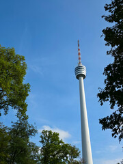 stuttgart tv tower appears above dense green treetops beneath an expansive blue sky offering a serene landmark view © Simon Dux Media