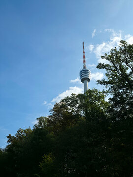 famous stuttgart tv tower stands elegantly beyond lush woodland trees against clear blue heavens creating an iconic german travel scene
