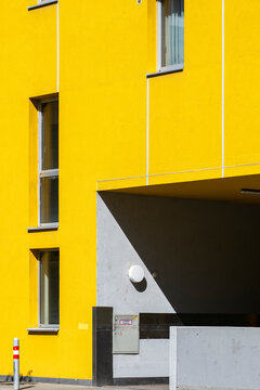 Yellow facade with a recessed entrance and hard sunlight creates a geometric urban building exterior with deep shadow in this architectural view
