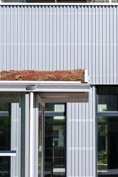 Minimal building facade with corrugated cladding doorway and windows presents clean geometric architecture in this modern exterior detail view
