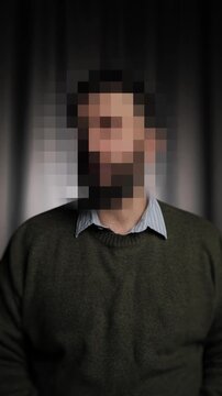 Hidden identity, hidden face, unknown person, silhouette interview. Man talking interviewer and looking at camera, his face is hidden. Vertical video
