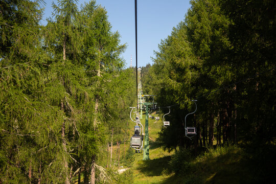 Scenic chairlift ride through the lush green forests of Monte San Vigilio in South Tyrol Italy