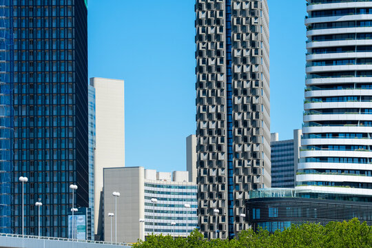 Modern high rise buildings create a varied urban skyline above green trees in Vienna Austria with contemporary architecture filling the city view