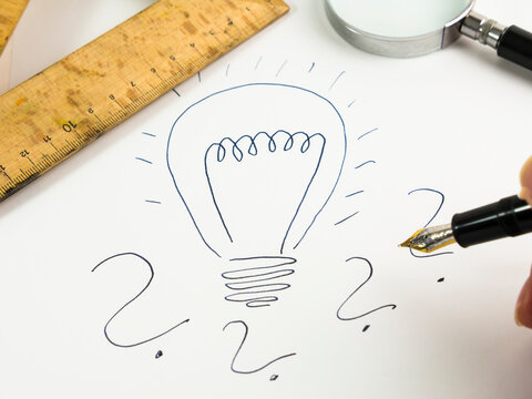 Drawn lightbulb and question marks on white paper
