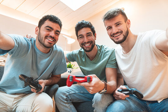 Happy friends with controllers taking selfie at home