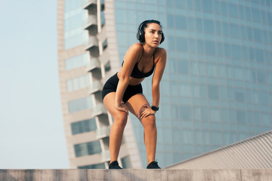 Athletic woman takes a rest during her outdoor city fitness workout