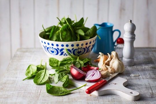 Fresh spinach leaves, red onion and garlic on chopping board, knife