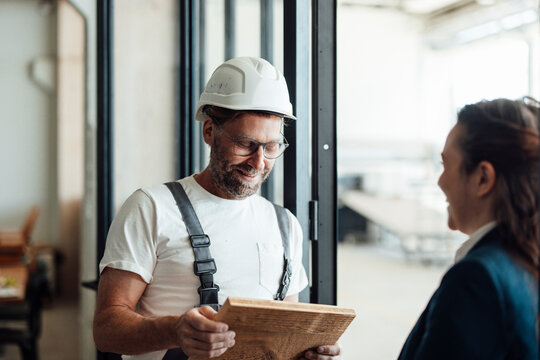 Carpenter and businesswoman discussing wood in the workshop