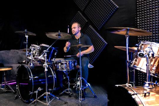 A man plays a drum kit in a rehearsal studio