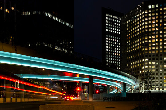 Night traffic light trails curve beneath illuminated office buildings in Paris France creating a dynamic urban business district scene