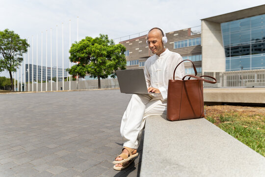 Smiling freelancer works on laptop at modern urban plaza in Barcelona