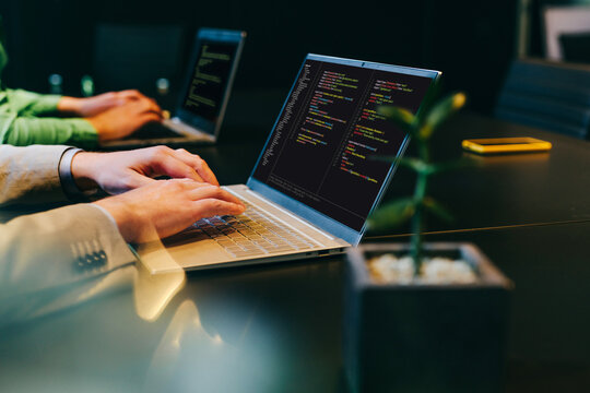 Businessman and colleague are coding on laptop in dark office