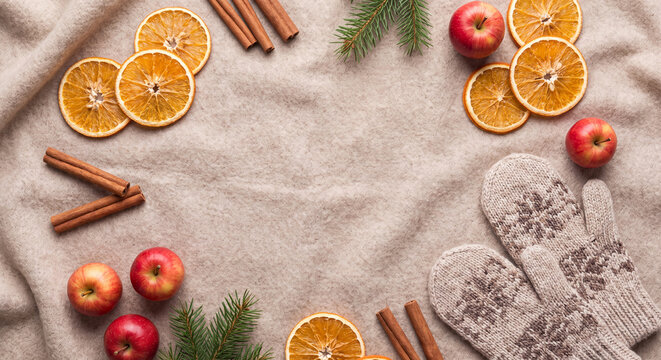Dried orange slices cinnamon mittens and red apples on a knitted blanket for winter flat lay background