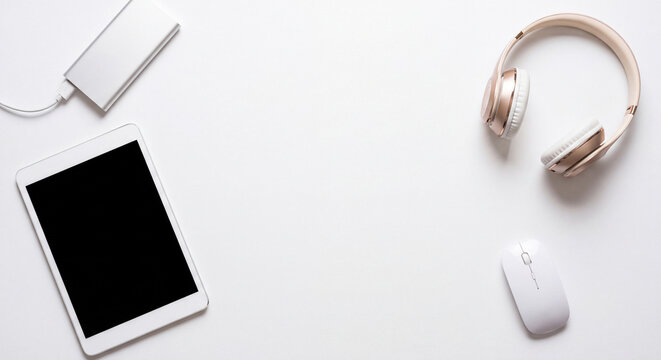 Top view flat lay of modern digital gadgets including tablet headphones computer mouse and accessories on a white background