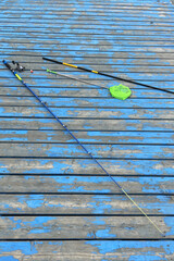 Fototapeta premium Fishing gear rests on a blue wooden dock beside the water in a sunny setting during the afternoon hours