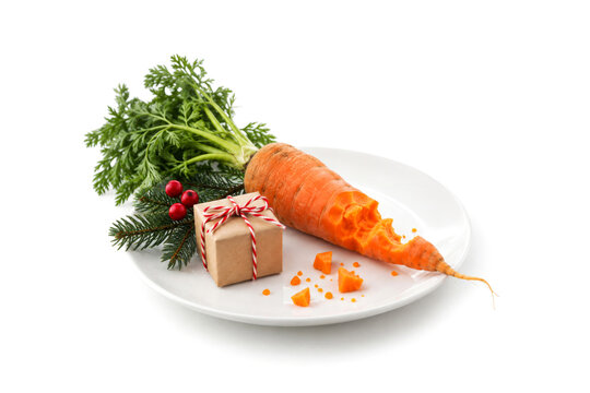 Reindeer snack carrot with a small gift and festive decorations on a white plate isolated on white background