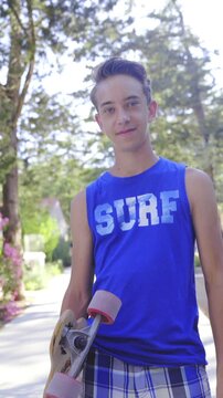 Teenager with skateboard puts down glasses smiling