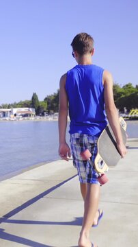 Teenager with longboard under hand walk beside sea beach