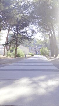 Walking on concrete path towards settlement through woods