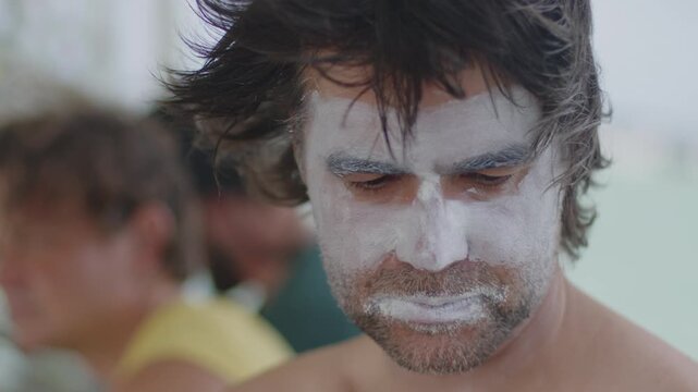 Close up portrait of the male surfer with his face covered with zinc sun protector. Surfers prepare for surfing session on the boat