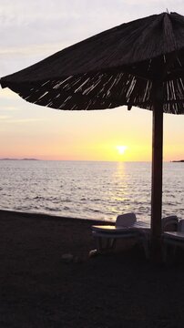 Lonely parasol silhouette on beach with sunset in background