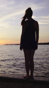 Woman silhouette stand on beach edge with view on sunset