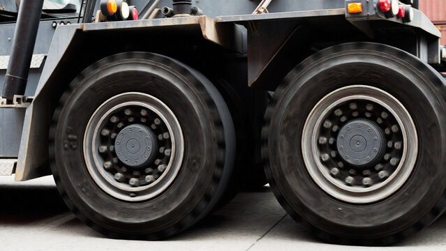 Large rubber wheels of a straddle carrier rolling past, overcast daylight