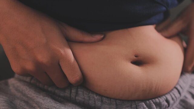 Overweight woman body with hands touching belly fat