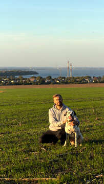 Man sitting with dalmatian dog on green field countryside landscape sunset