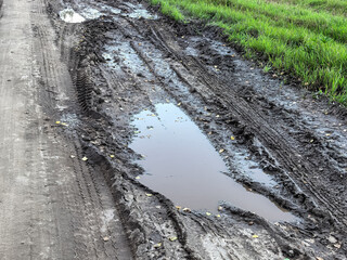 Long narrow puddle in deep muddy ruts on a dirt road © Vertstyle