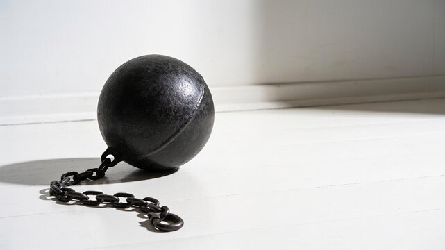 Black Iron Ball and Chain on White Floor, Debt Burden