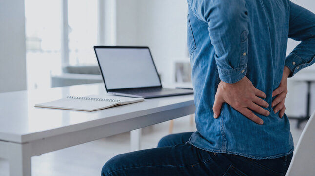 Man suffering from severe lower back pain and muscle strain while working desk