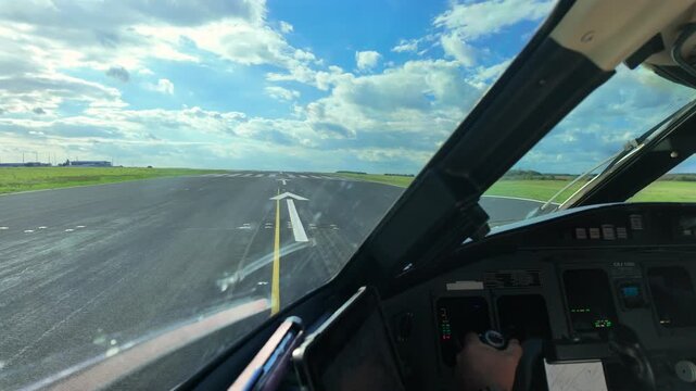 Immersive pilot perspective in the runway threshold starting the takeoff run with broken clouds in a blue sky. caucasian pilot hand on the flight controls. 4K