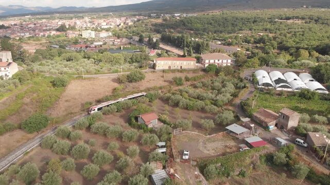 Aerial drone shot following the Ferrovia Circumetnea train as it enters the town of Randazzo in Sicily
